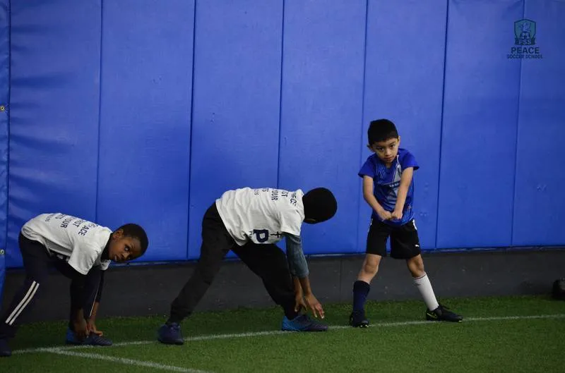 Coach leading faith-based devotional with youth soccer players at Peace Soccer School